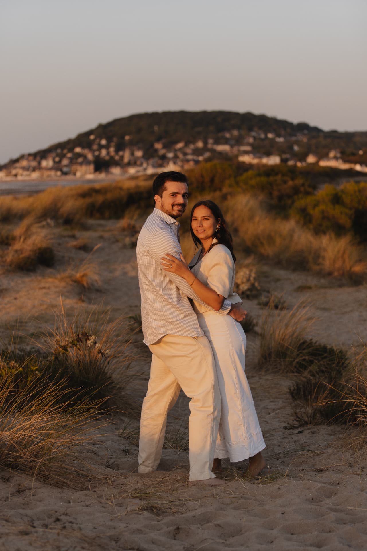 Juliette et Alexandre enlacés dans les dunes au coucher du soleil