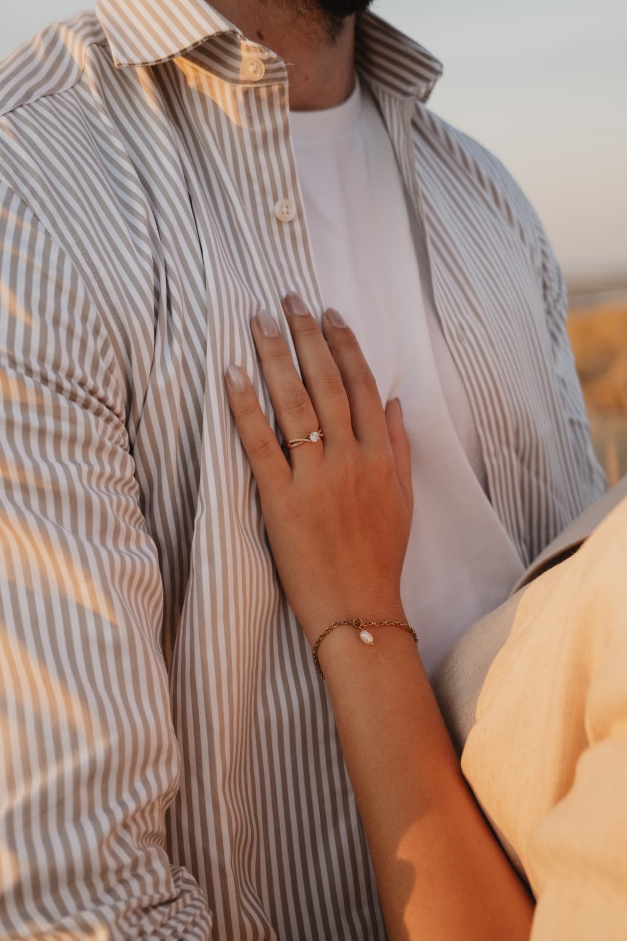 La main de la mariée, bague de fiançailles, posée sur la chemise du marié
